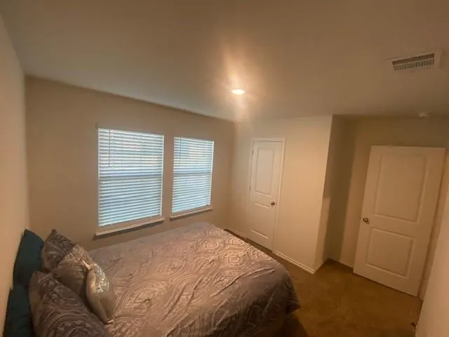 a bed sitting in a bedroom next to a window and dresser