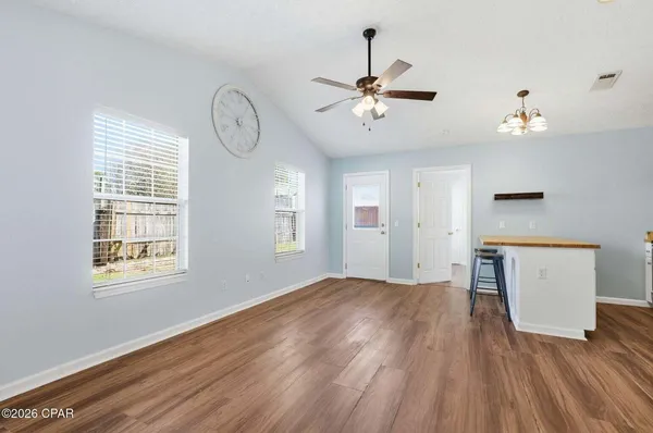 a view of an empty room with a window and wooden floor