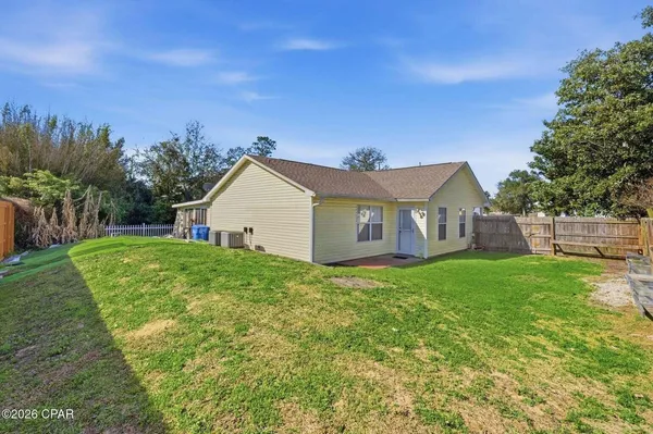 a view of a yard in front of a house with plants and large trees