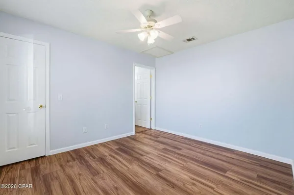 a view of a room with wooden floor and a ceiling fan