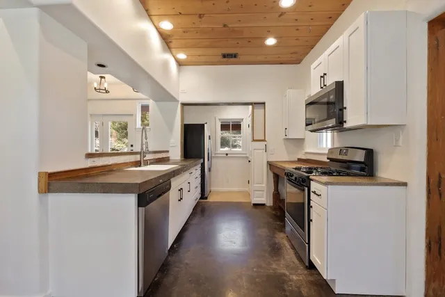 a large kitchen with stainless steel appliances granite countertop a stove and a sink