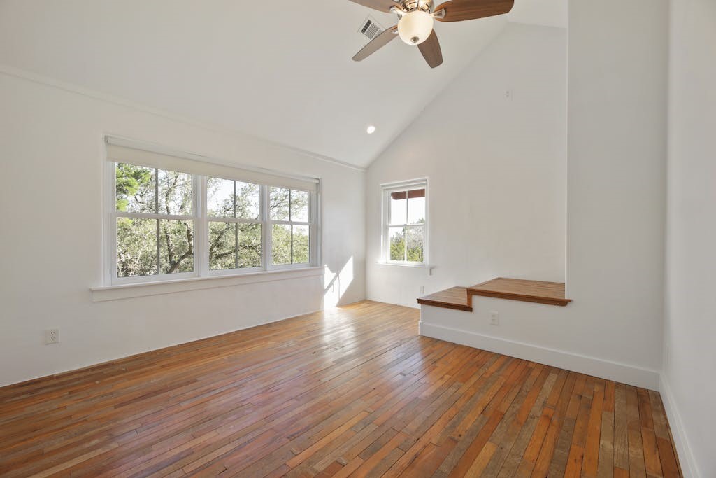 1612 The High Road Austin, TX 78746 - Photo 16 of 26 an empty room with wooden floor fan and windows