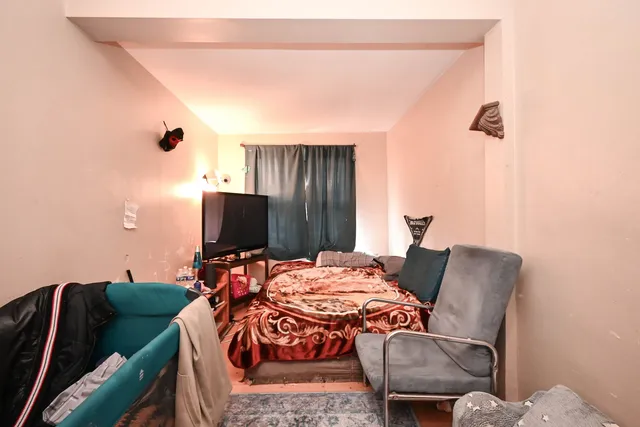 a bed sitting in a bedroom next to a window with pc on it