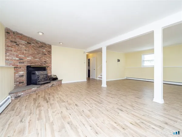 a view of empty room with wooden floor and fireplace