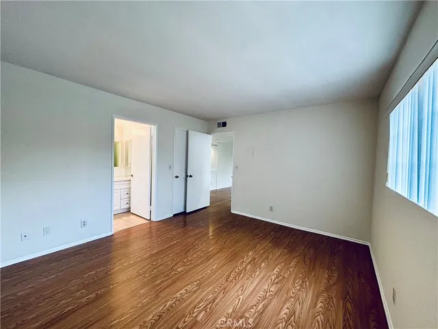 an empty room with wooden floor and window