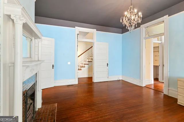 a view of an empty room with wooden floor fireplace and a window