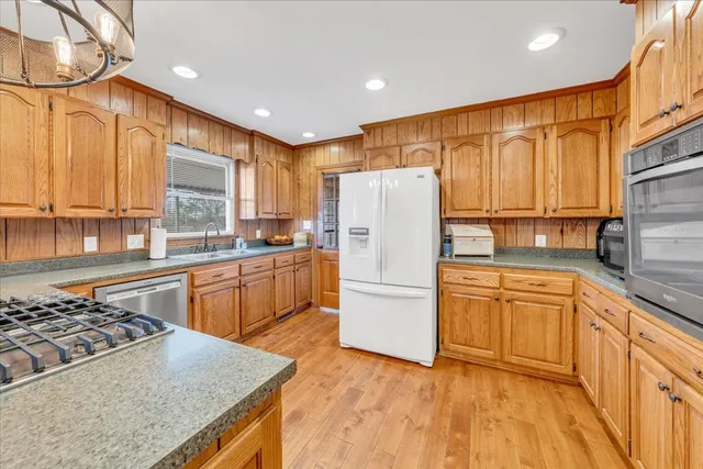 a kitchen with granite countertop wooden cabinets a sink and dishwasher next to a window