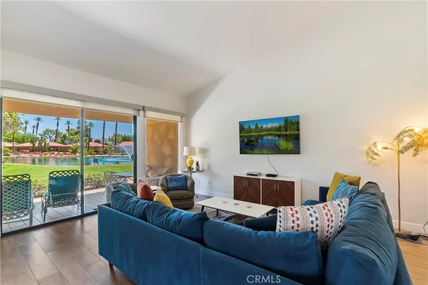a living room with couch floor to ceiling window and a flat screen tv