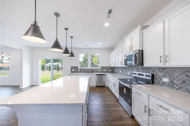 a large kitchen with stainless steel appliances granite countertop a stove a sink a kitchen island with wooden cabinets and floor