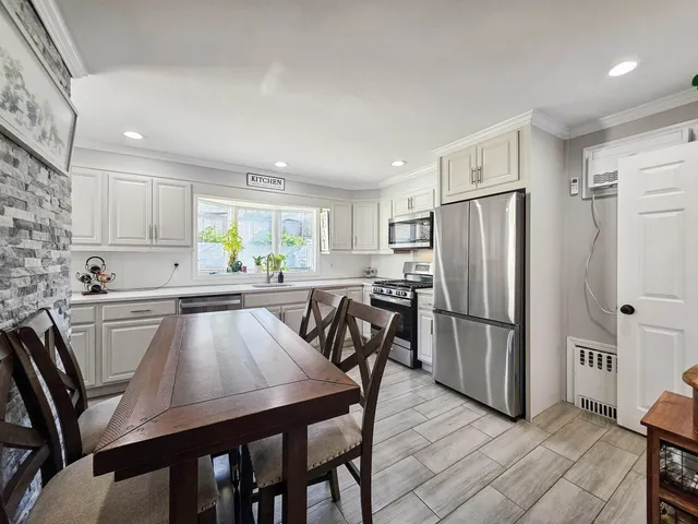 a kitchen with stainless steel appliances a table chairs microwave and refrigerator