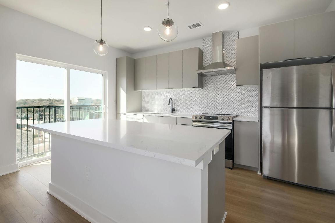 2500 Longview Street, Unit 501 Austin, TX 78705 - Photo 7 of 23 a kitchen with stainless steel appliances granite countertop a refrigerator a sink dishwasher a stove and a refrigerator with wooden floor