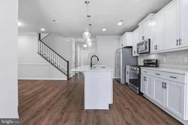 a kitchen with a sink stainless steel appliances and wooden floor