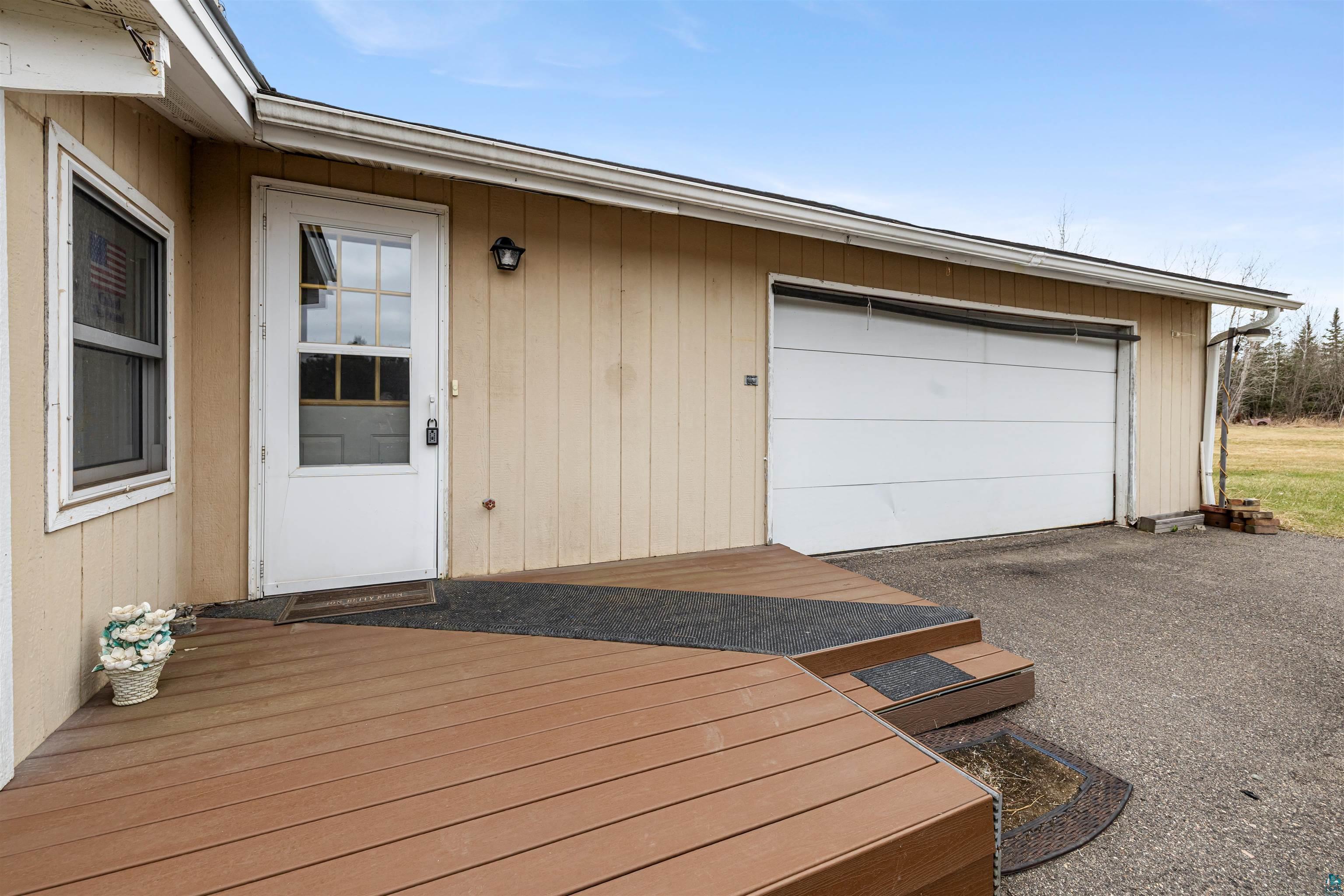 11574 Town Line Road Hibbing, MN 55746 - Photo 23 of 41 Exterior featuring neutral siding, a white garage door, and a brown wood-finish deck with steps