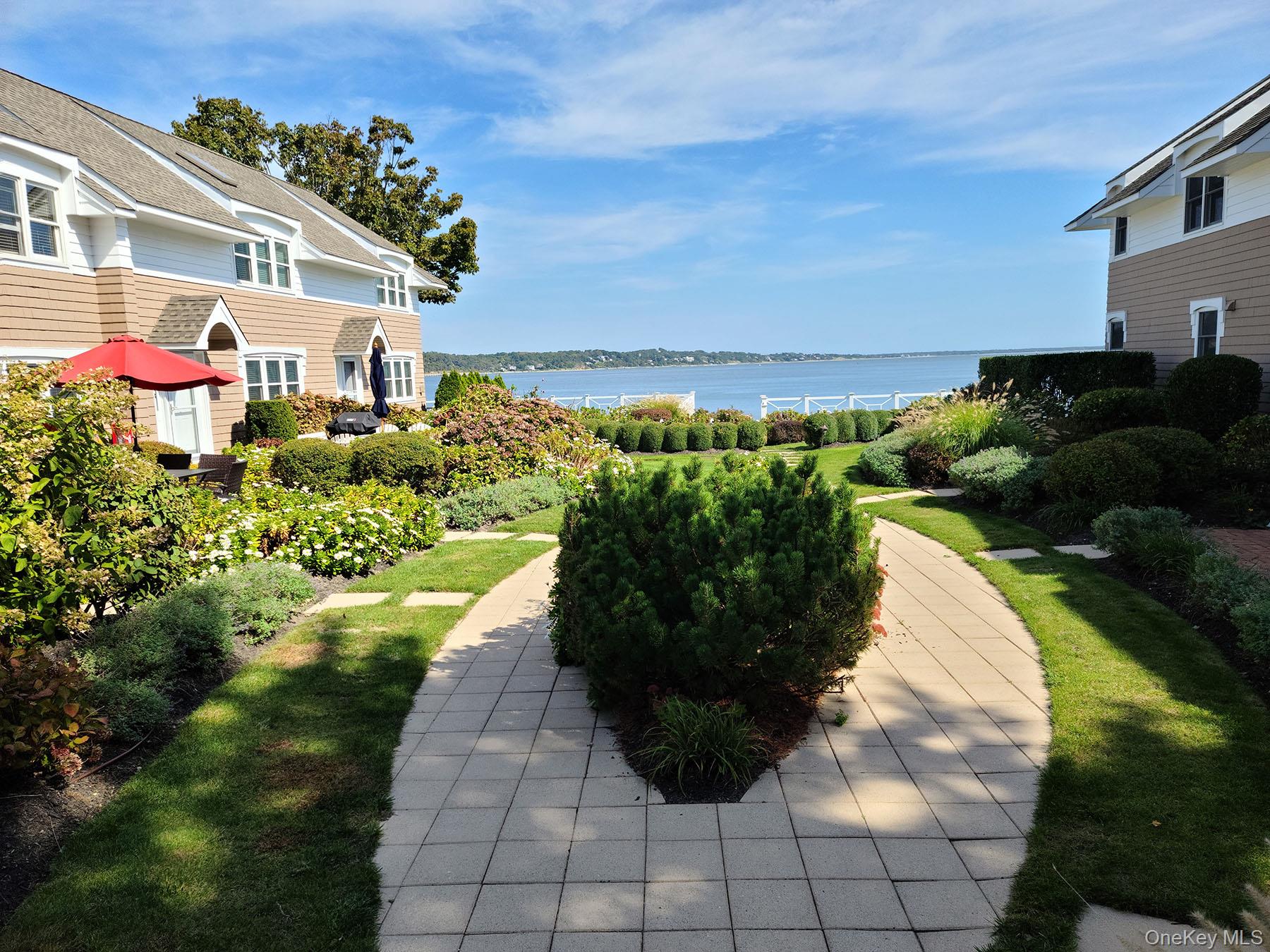 62 Canoe Place Road, Unit 627 Hampton Bays, NY 11946 - Photo 17 of 27 a view of a white house with a yard and potted plants