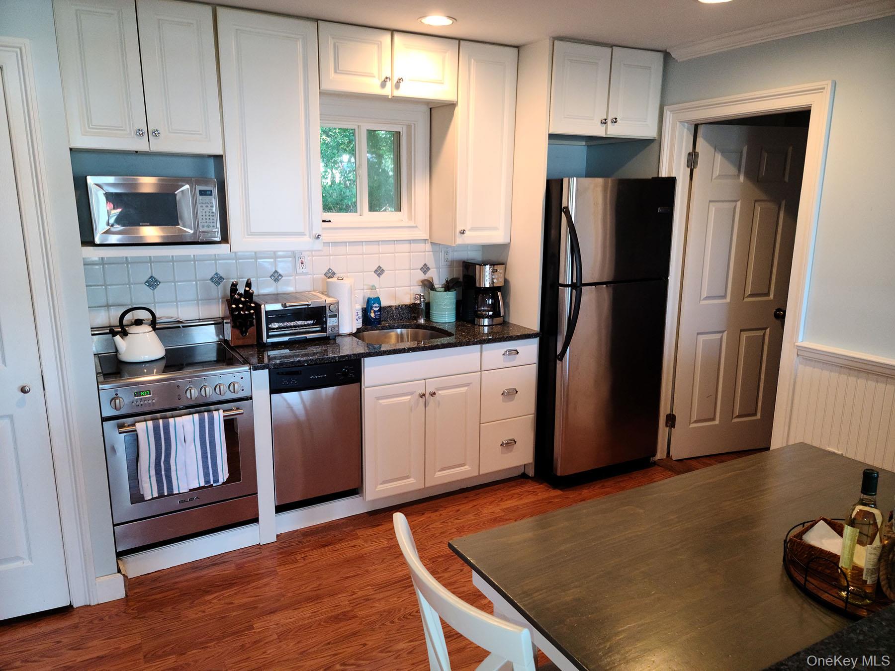 62 Canoe Place Road, Unit 627 Hampton Bays, NY 11946 - Photo 9 of 27 a kitchen with a refrigerator sink and cabinets