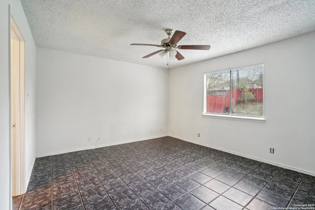 an empty room with windows and fan