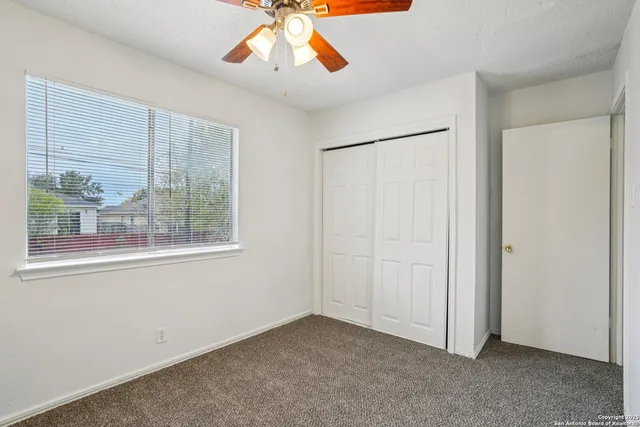 an empty room with a window and a fan