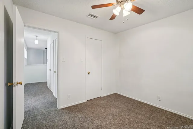 an empty room with chandelier fan