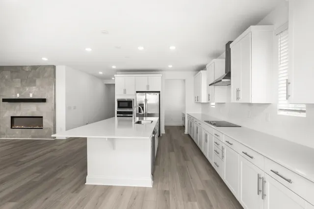 a large kitchen with stainless steel appliances a large counter top a sink a stove and a refrigerator