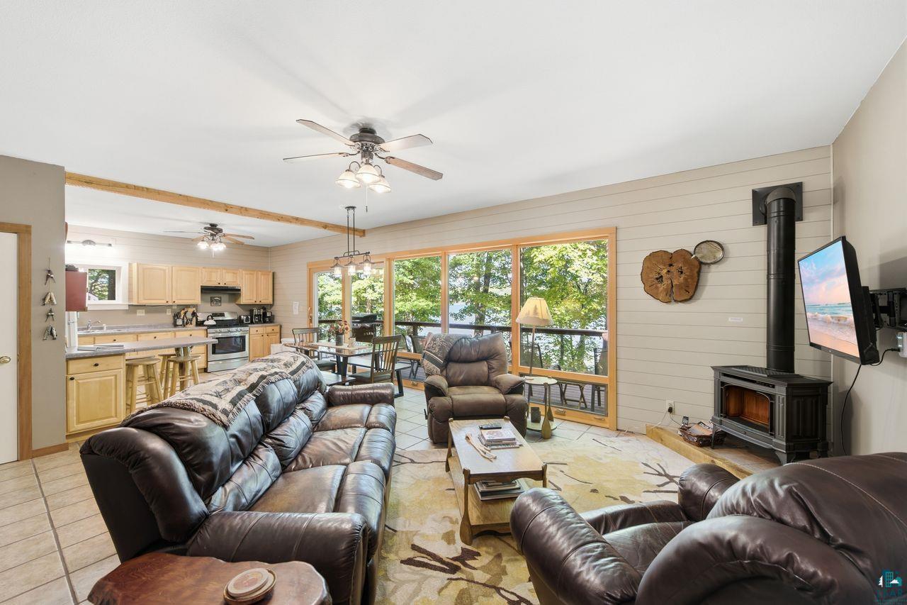 69085 East Long Lake Road Iron River, WI 54847 - Photo 9 of 33 Open-concept living area with a wood-burning stove, wood-finish flooring, natural wood cabinetry, and expansive glass doors opening to outdoor space