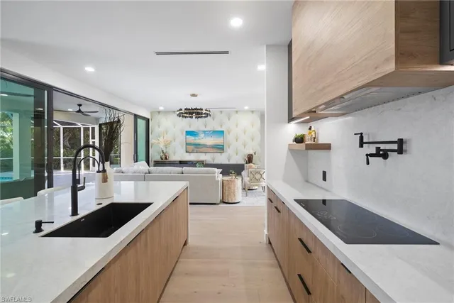 a large white kitchen with stainless steel appliances a sink and cabinets