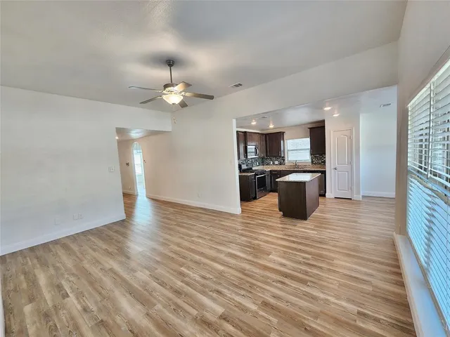 a view of a kitchen with wooden floor and a ceiling fan