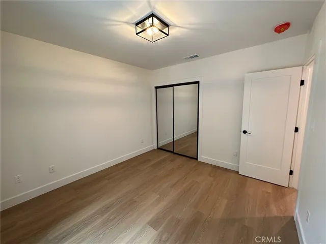 an empty room with wooden floor and ceiling fan