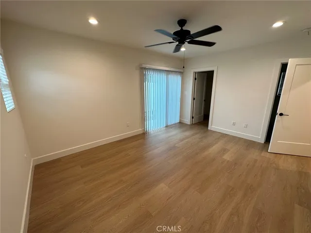 an empty room with wooden floor and a ceiling fan