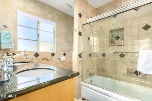 a bathroom with a granite countertop sink and a bathtub