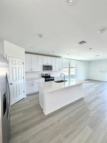a large white kitchen with white cabinets a sink and appliances
