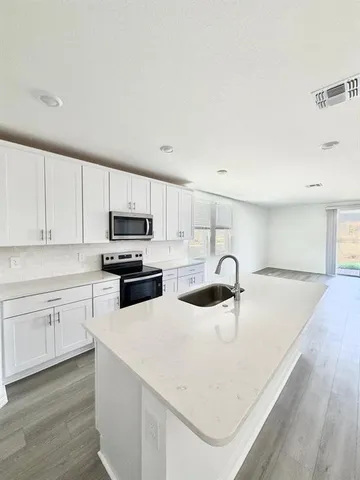 a kitchen with granite countertop a sink a stove and cabinets