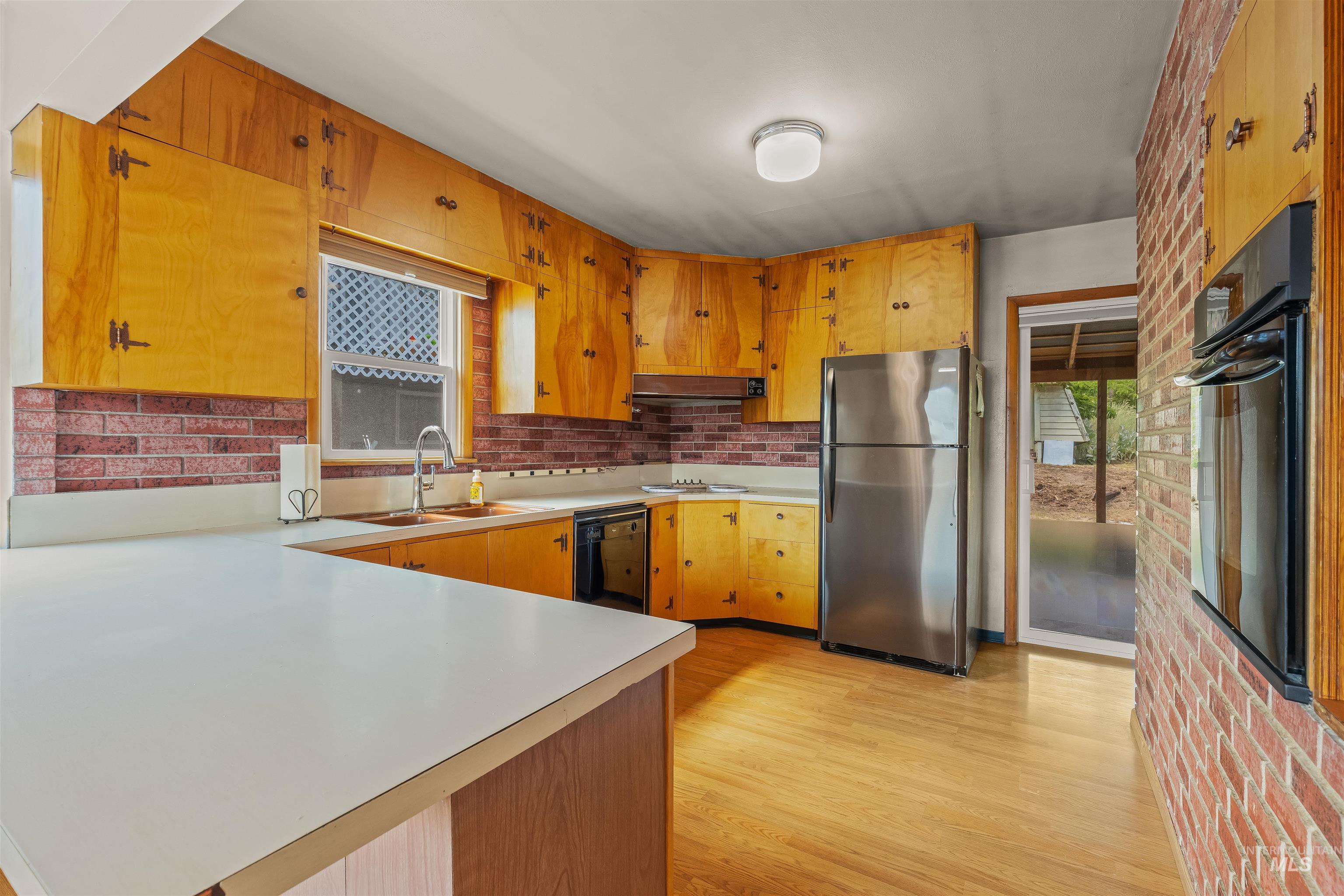1663 9th Avenue Lewiston, ID 83501 - Photo 13 of 36 Kitchen featuring wood-finish cabinetry, white countertops, brick-style backsplash, stainless steel refrigerator, and wood-finish flooring