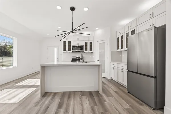 a kitchen with stainless steel appliances a refrigerator a stove a sink and white cabinets with wooden floor