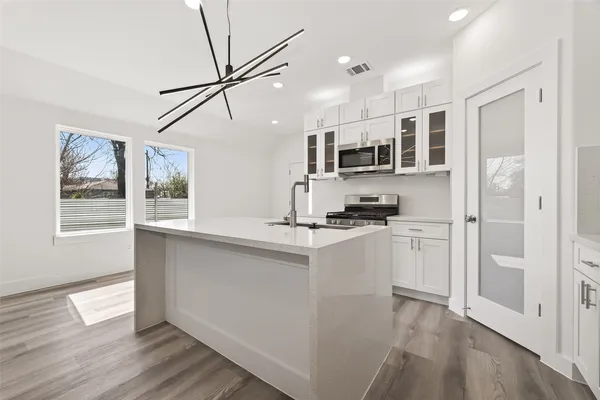a kitchen that has a sink and a stove with wooden floor