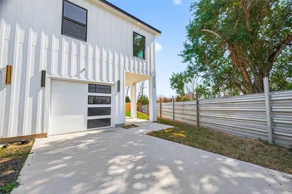 a view of a house with a small yard and large tree