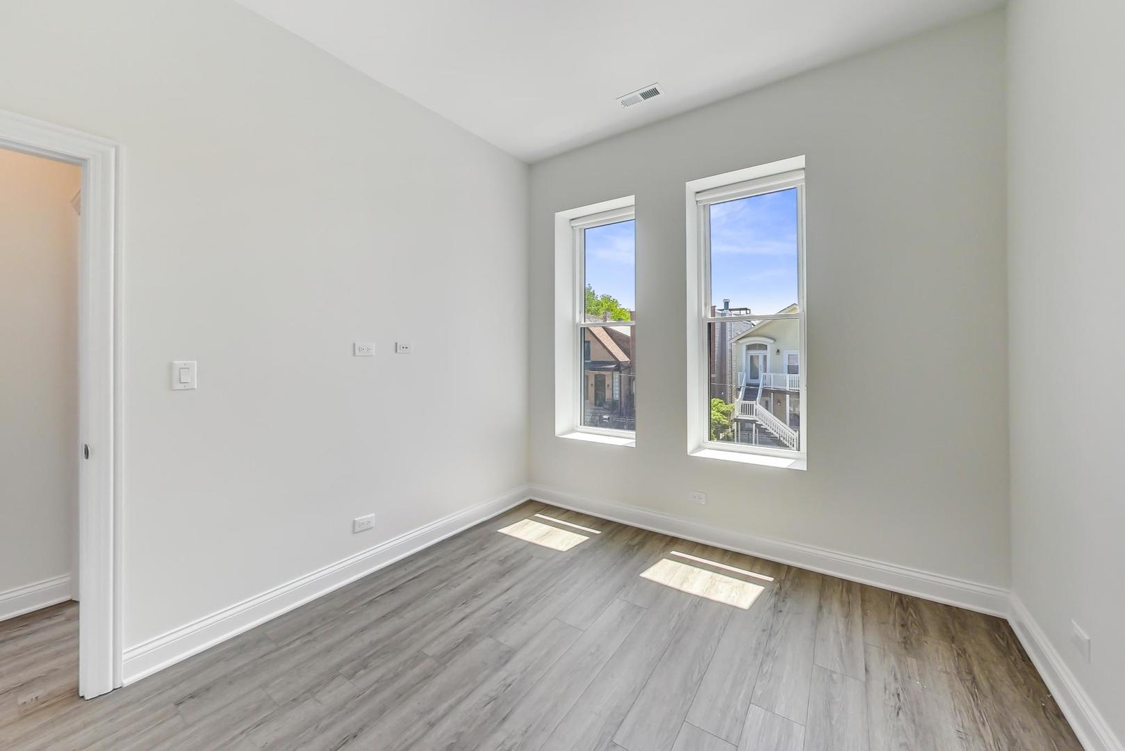 2312 West Ohio Street, Unit 2S Chicago, IL 60612 - Photo 9 of 18 an empty room with wooden floor and windows