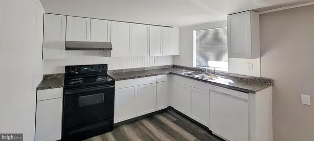 a kitchen with granite countertop white cabinets and a stove