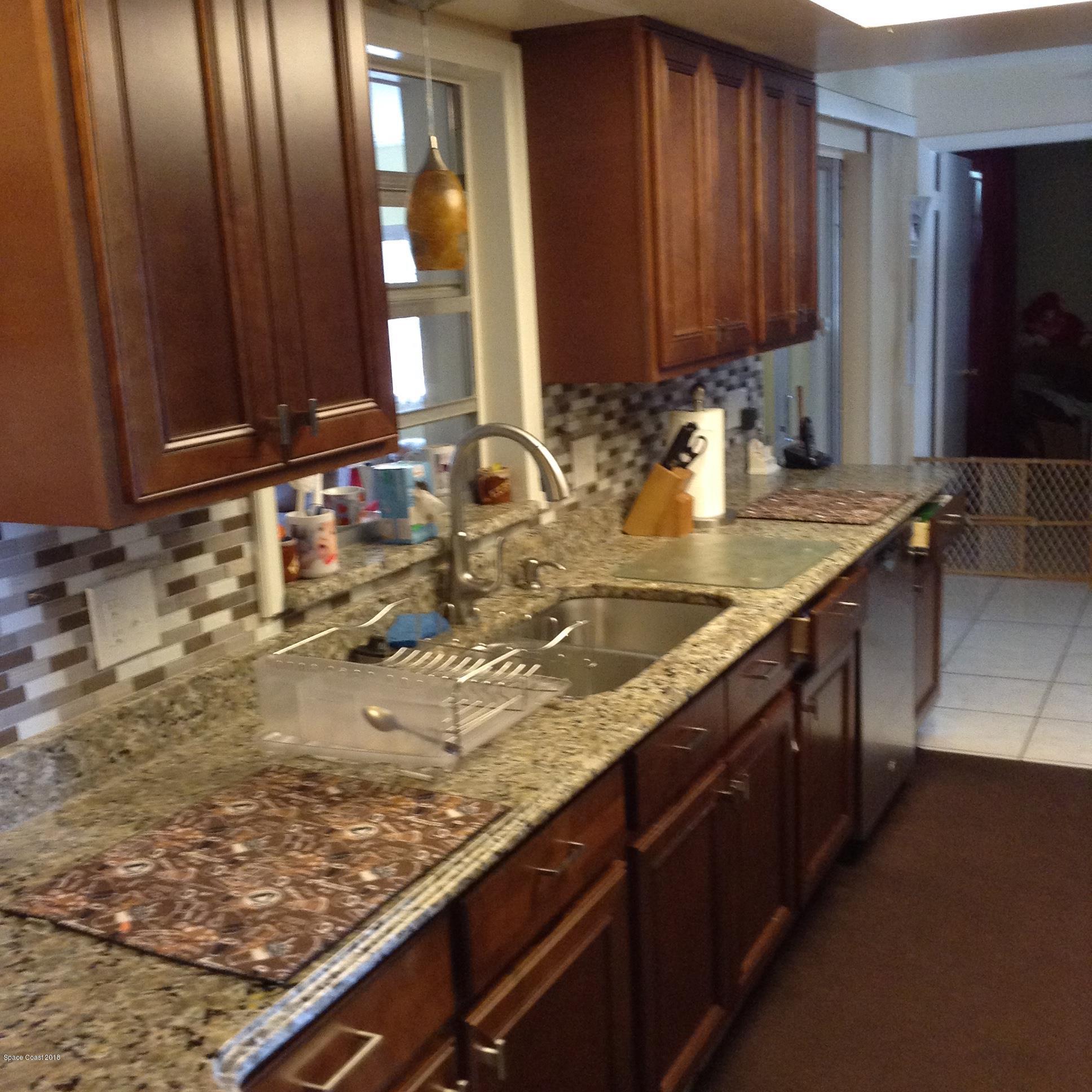 501 Croton Road Melbourne, FL 32935 - Photo 14 of 20 a kitchen with granite countertop stainless steel appliances a sink window and cabinets