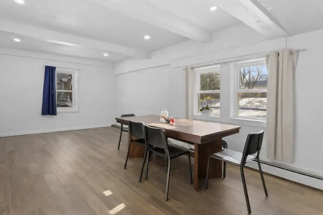 a view of a dining room and livingroom with furniture wooden floor a rug a painting and a chandelier