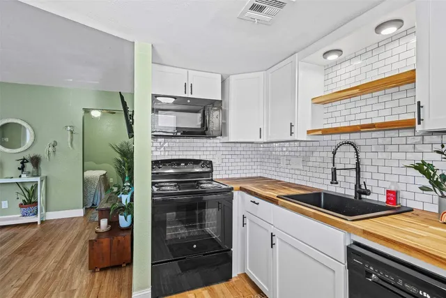 a kitchen with stainless steel appliances a sink dishwasher stove refrigerator and cabinets with wooden floor