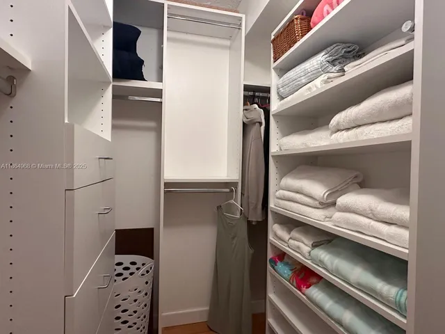 a view of walk in closet with clothes and shoes