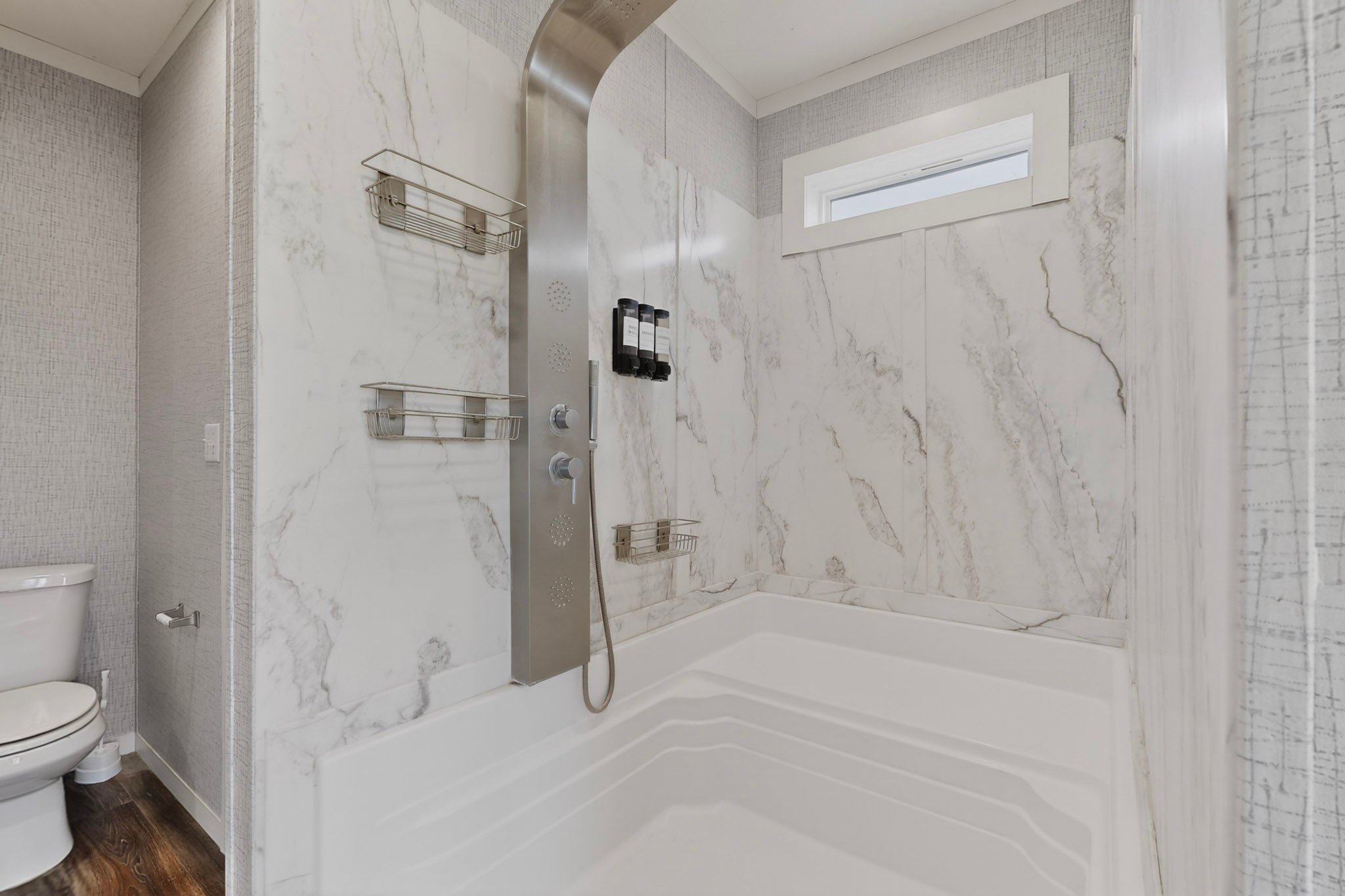 664 Garrett Road Yoakum, TX 77995 - Photo 11 of 39 Shower with white marble-patterned paneling, a multi-function shower panel, and integrated shelving