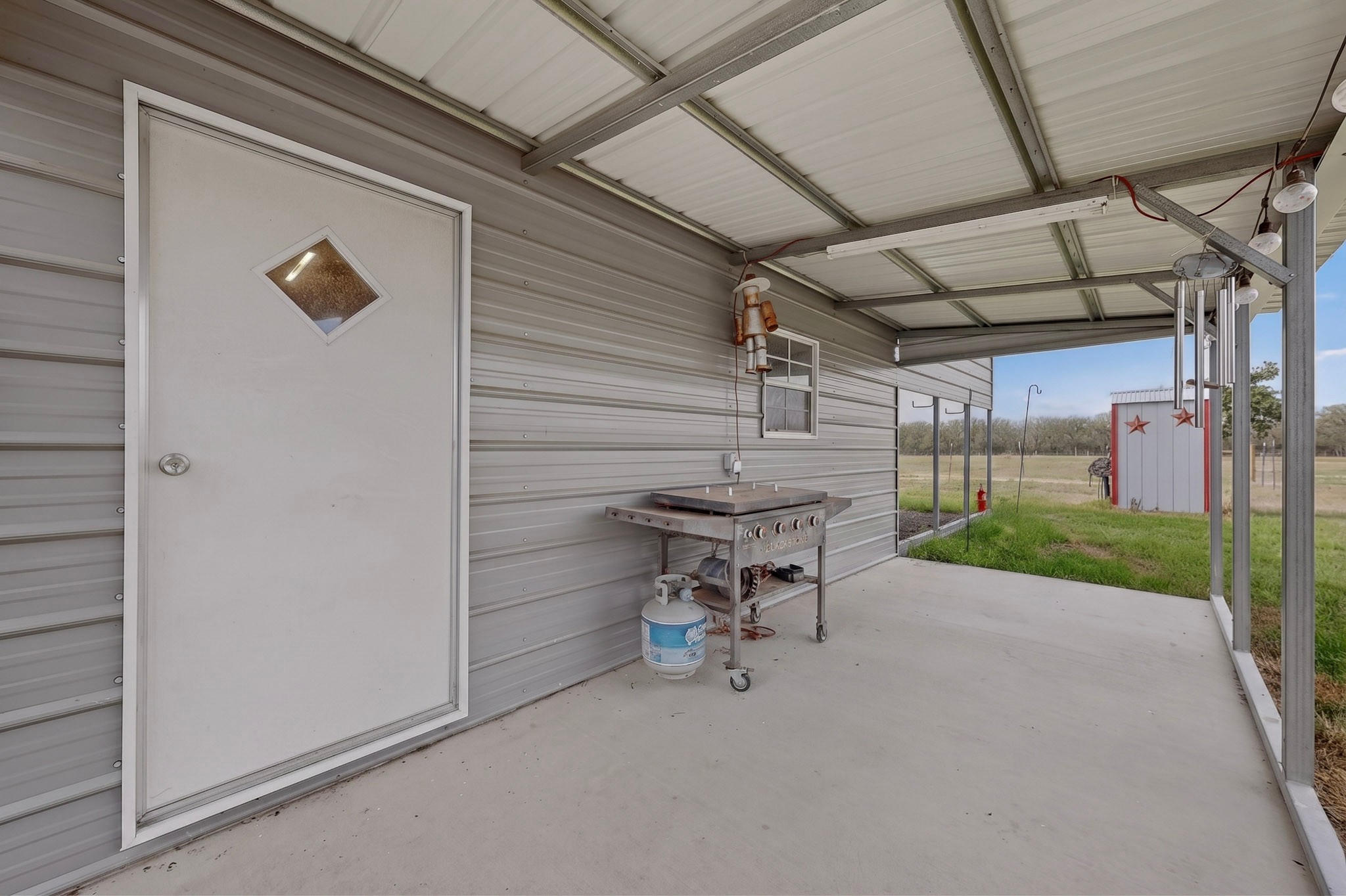 664 Garrett Road Yoakum, TX 77995 - Photo 13 of 39 Covered concrete patio space featuring a metal overhead structure and corrugated metal siding