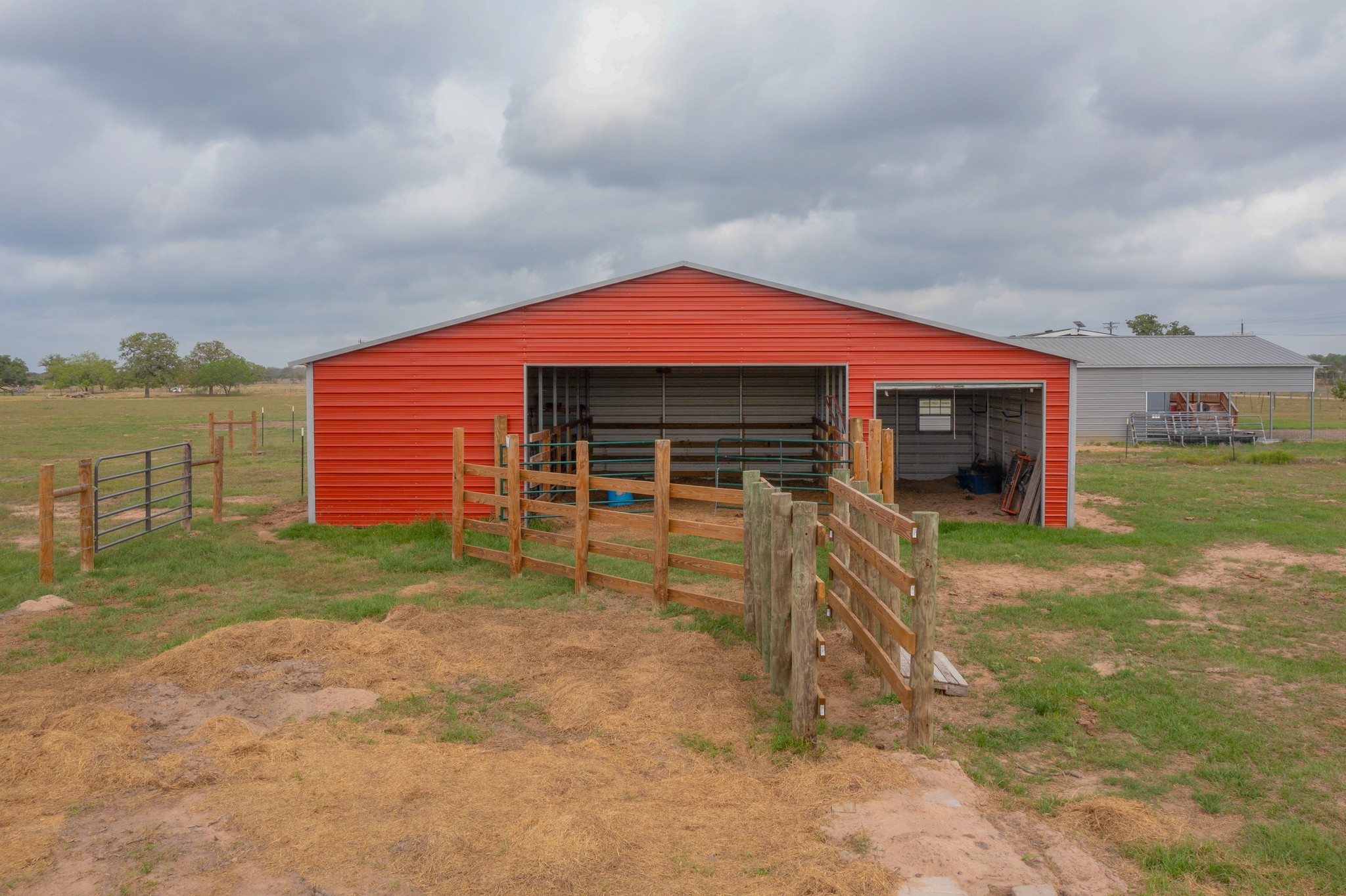 664 Garrett Road Yoakum, TX 77995 - Photo 17 of 39 Red metal barn structure featuring multiple open bays, a metal roof, and interior fencing