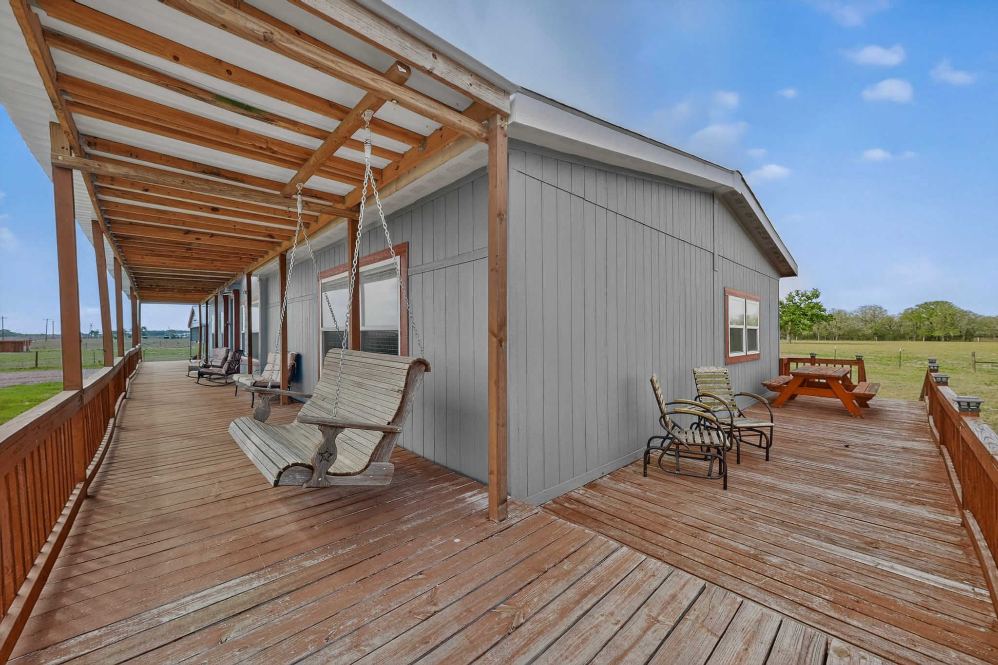 664 Garrett Road Yoakum, TX 77995 - Photo 20 of 39 Expansive wood-finish porch featuring a covered section, open-air deck, and a porch swing