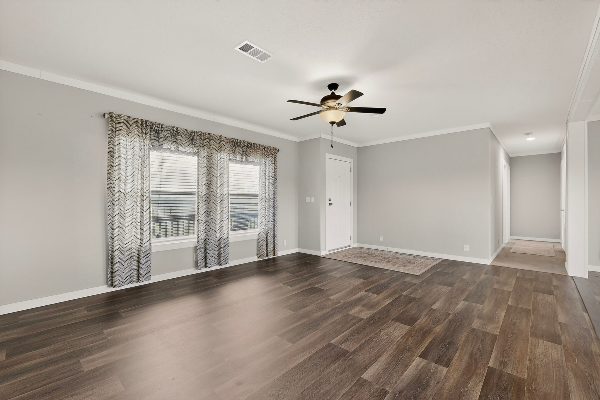 664 Garrett Road Yoakum, TX 77995 - Photo 28 of 39 Spacious living area featuring ,Beauflor luxury vinyl plank flooring, light gray walls, white baseboards, and crown molding