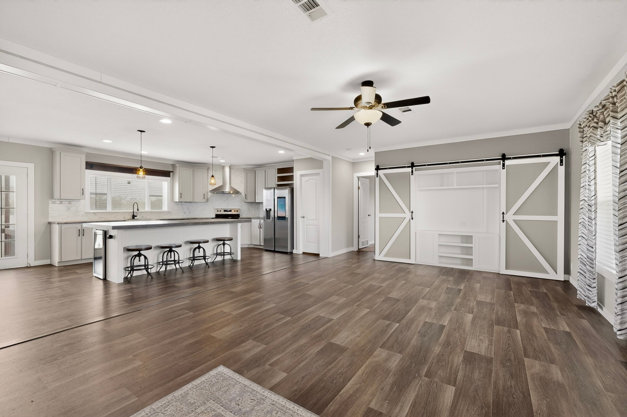 664 Garrett Road Yoakum, TX 77995 - Photo 29 of 39 Open-concept living area featuring, crown molding trim, Beauflor luxury vinyl plank flooring, a contemporary kitchen with a large island, stainless steel appliances, and pendant lighting