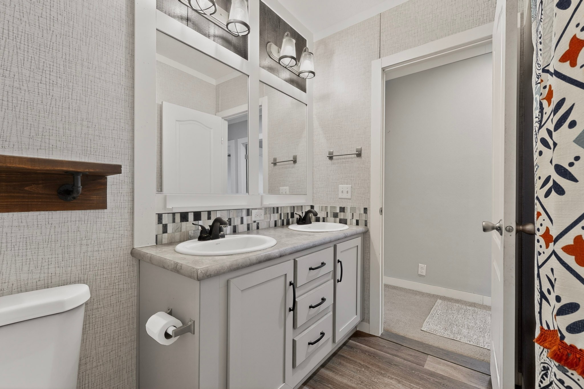 664 Garrett Road Yoakum, TX 77995 - Photo 36 of 39 Bathroom vanity featuring dual sinks with matte black faucets, light gray cabinetry, and a mosaic tile backsplash