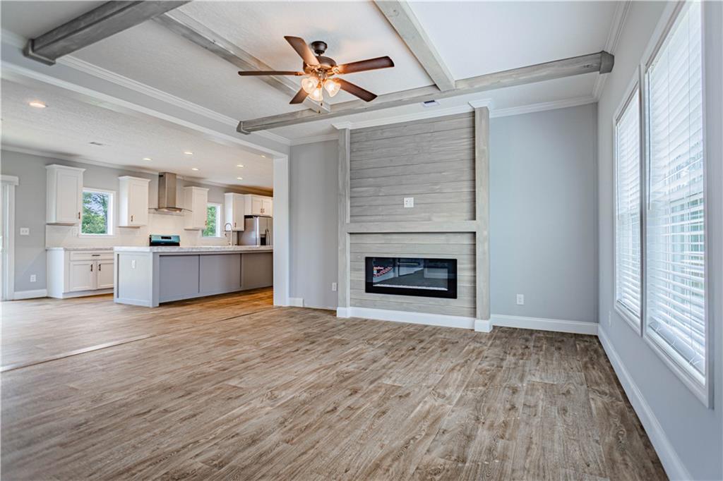 Open-concept space featuring wood-finish flooring, a ceiling fan, and a fireplace with a wood-plank surround