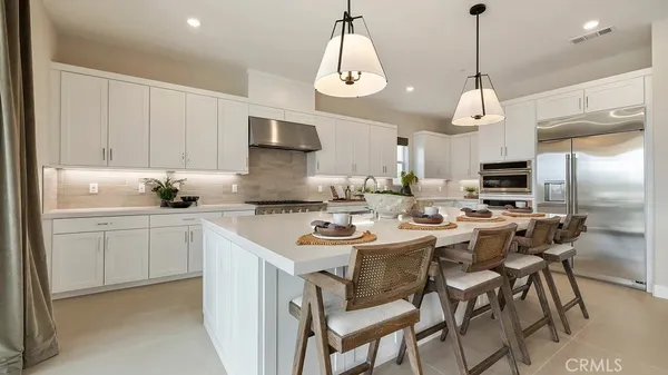 a kitchen with stainless steel appliances a dining table chairs and sink